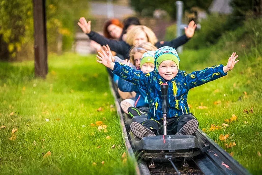 Kinder und Eltern auf der Sommerrodelbahn in der Erlebniswelt Seiffen