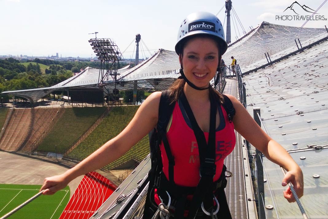 Reisebloggerin Biggi Bauer mit Sicherung für den Flying Fox über dem Olympiastadion in München